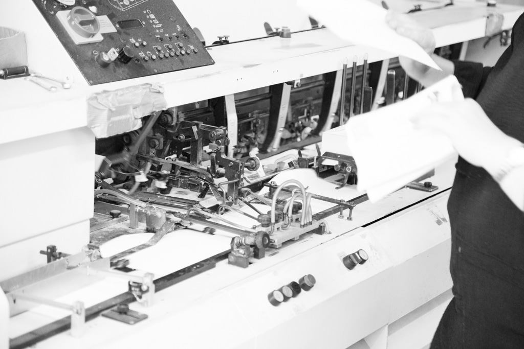 Mitarbeiterin bedient eine Kuvertiermaschine